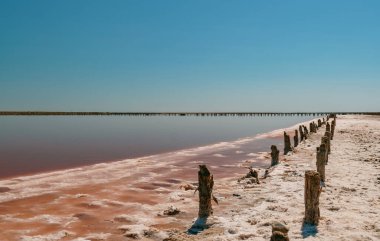 Pembe tuz gölünde gün batımı, pembe tuz çıkarmak için eski bir maden. Tuzla kaplanmış tahta çiviler.
