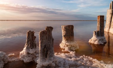 Pembe tuz gölünde gün batımı, pembe tuz çıkarmak için eski bir maden. Tuzla kaplanmış tahta çiviler.