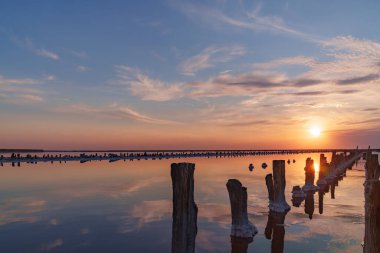 Pembe tuz gölünde gün batımı, pembe tuz çıkarmak için eski bir maden. Tuzla kaplanmış tahta çiviler..