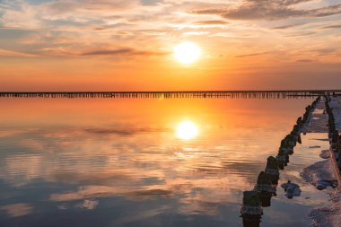 Pembe tuz gölünde gün batımı, pembe tuz çıkarmak için eski bir maden. Tuzla kaplanmış tahta çiviler.
