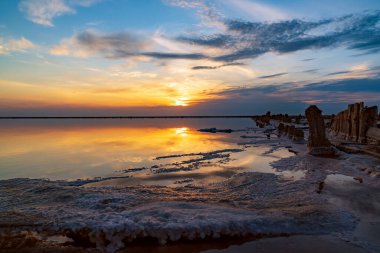 Pembe tuz gölünde gün batımı, pembe tuz çıkarmak için eski bir maden. Tuzla kaplanmış tahta çiviler.