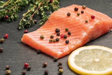 Koyu arkaplanda çiğ somon filetosu. Limonlu, kekikli ve biberli alabalık filetosu. Vahşi Atlantik Balığı yaklaşıyor. Sağlıklı yemek..