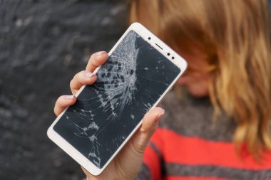 Elinde kırık ekran telefonu olan bir kadın..