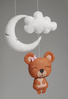 Çocuklar için yapılmış renkli ve çevre dostu bir cep telefonu. Ayı, ay ve bulut oyuncaklarından oluşur. Gri arkaplanda el yapımı.