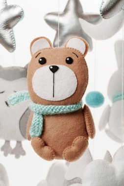 Ayı şeklinde keçeli bir oyuncak, çocuk arabasının bir parçası. Beyaz bir arka planda. Çocuklar için yapılmış renkli ve çevre dostu çocuk cep telefonu.