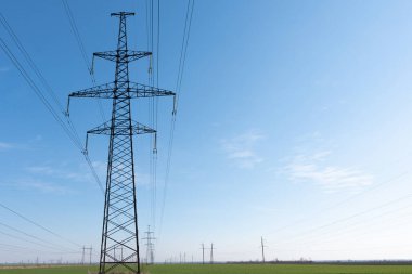 Mavi gökyüzü ve yeşil çayırlar üzerindeki elektrik direkleri..