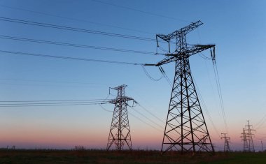 Gün batımında ya da gün doğumunda yüksek voltajlı elektrik hatları. Yüksek voltajlı elektrik iletim kulesi.