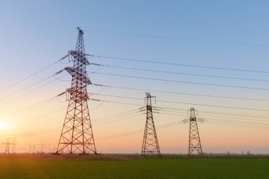 Mavi gökyüzü ve yeşil çayırlar üzerindeki elektrik direkleri..