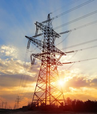 Akşamki elektrik iletim kulesinin silueti. Bir enerji santralinden bir şehre güç aktarımı