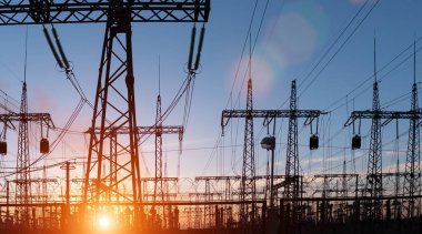 Dramatik günbatımı arka planında elektrik santrali silueti.