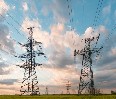 Elektrik hatları ve yüksek gerilim hatları yaz günü yağlı tohumlarla yapılan tecavüzün arka planına karşı. Yeşil enerji. Tarımsal alanlar yoluyla elektrik aktarımı.