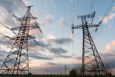 Akşamki elektrik iletim kulesinin silueti. Bir enerji santralinden bir şehre güç aktarımı