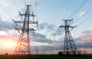 Gün batımında ya da gün doğumunda yüksek voltajlı elektrik hatları. Yüksek voltajlı elektrik iletim kulesi.