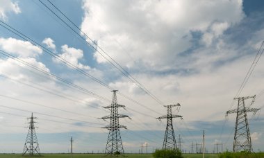 Mavi gökyüzü ve yeşil çayırlar üzerindeki elektrik direkleri..