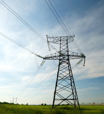 Mavi gökyüzü ve yeşil çayırlar üzerindeki elektrik direkleri..