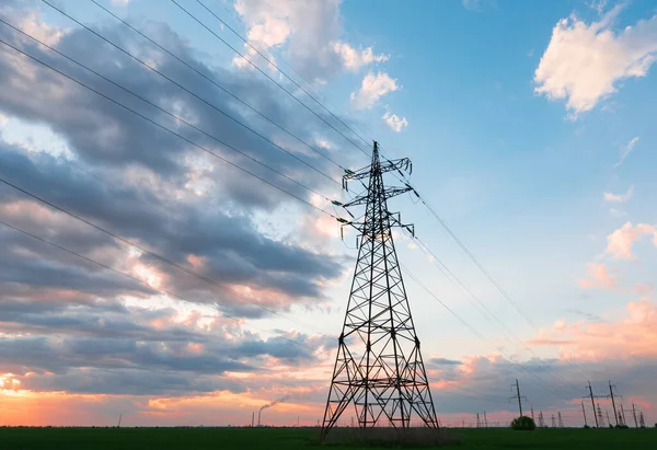 青い空と緑の牧草地のパノラマ上の電柱の電気網 — ストック写真
