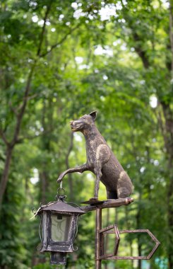 Sokak lambası, elinde lamba tutan köpek şeklinde. Metal heykel.