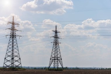 Mavi gökyüzüne karşı yüksek voltajlı elektrik hatlarını destekliyor. Elektrik endüstrisi