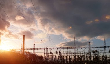 Elektrik direkleri ve elektrik hatları alacakaranlıkta. Sanayi manzarası.