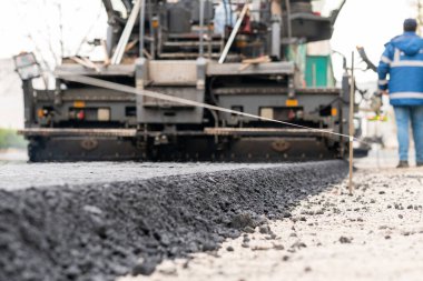 Paver makinesi şehir yoluna taze asfalt seriyor..