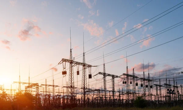 Dramatik günbatımı arka planında elektrik santrali silueti.