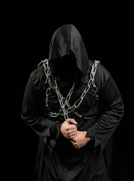 A man in a killer costume holds a knife in his hand on a black background. Scary Halloween costume.