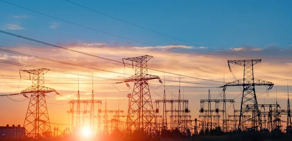 distribution electric substation with power lines and transformers, at sunset