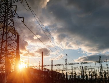 Gün batımında yüksek voltajlı elektrik hatları. Termik santral. Yüksek voltajlı trafo alt istasyonu.