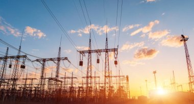 Gün batımında yüksek voltajlı elektrik hatları. Termik santral. Yüksek voltajlı trafo alt istasyonu.