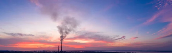 Panorama of an industrial landscape. Thermal power plant on a background of red sunset, aerial view.
