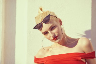 Stüdyoda poz veren güneş gözlüklü ve kırmızı dudaklı güzel bir kadın.