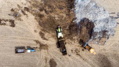 Yükleyici traktöre tarlaları gübrelemek için gübre gübresi içeren bir karavan yüklüyor. Organik tarım gelişimi kavramı. Çevresel bir sorun. Hava görünümü.