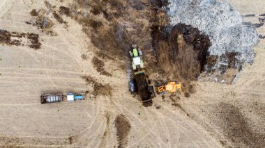 Yükleyici traktöre tarlaları gübrelemek için gübre gübresi içeren bir karavan yüklüyor. Organik tarım gelişimi kavramı. Çevresel bir sorun. Hava görünümü.