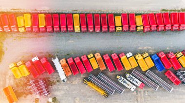 Otoparktaki çok renkli damperli kamyonların, römorkların, kamyonların ve şasilerin havadan görüntüsü. Ağır iş araçları üreten bir fabrika. Üst görünüm.