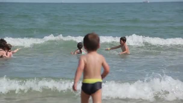 Ευτυχής παιδιά άλμα μέσα από τα κύματα της θάλασσας — Αρχείο Βίντεο