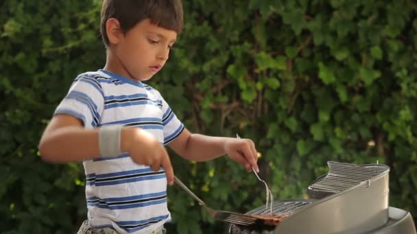 Pojke matlagning biff på grillen. — Stockvideo