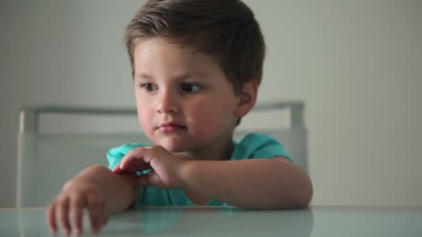 Przemyślane Mały Chłopiec Siedzi Przy Stole Marzy Czymś — Wideo stockowe