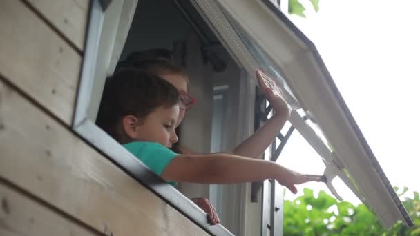 Menino e menina abrir a janela e olhar para a rua — Vídeo de Stock