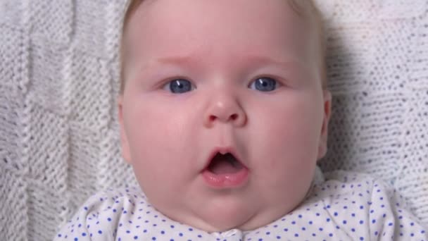 Şirin mavi gözlü bebek gülümsüyor ve kitap — Stok video