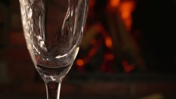 Champagne hälls i ett glas på en bakgrund av brand — Stockvideo