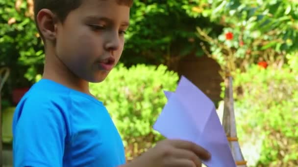 Мальчик запускает бумажный самолет — стоковое видео