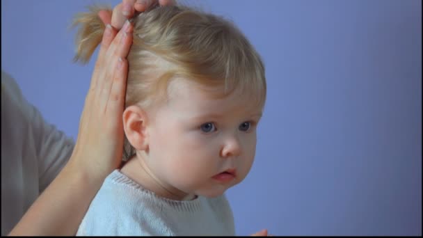 Мама делает хвостик из волос своей маленькой дочери — стоковое видео