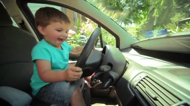 Kleiner Junge spielt hinterm Steuer eines großen Autos — Stockvideo