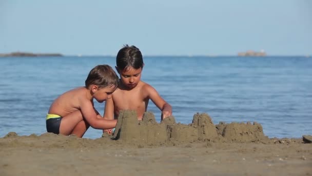 Twee jongens bouwen zandkastelen — Stockvideo