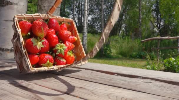 Strawberry hälls från en korg på ett träbord — Stockvideo