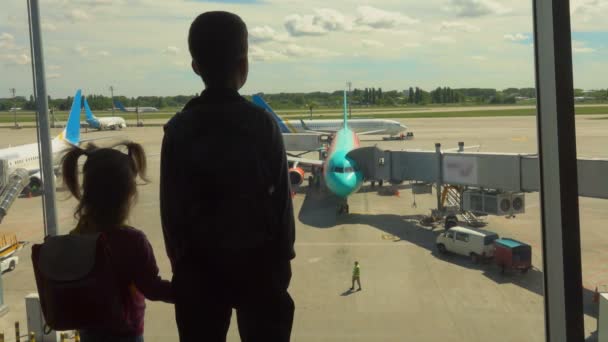 Menino e uma menina estão de pé no aeroporto — Vídeo de Stock