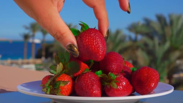 Mano pone una fresa jugosa grande de un plato — Vídeo de stock