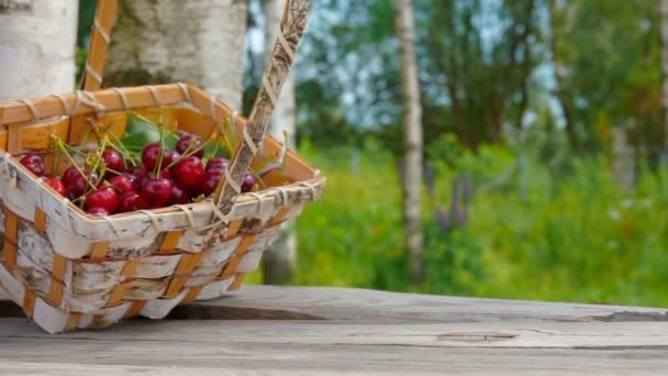 Cesta com cerejas maduras cai sobre uma mesa de madeira — Vídeo de Stock