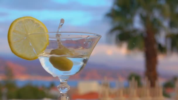 Оливка падает в бокал с мартини — стоковое видео