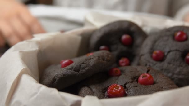 Hand zet chocolade koekjes met cranberries in vak — Stockvideo